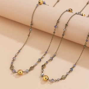 Close-up of bohemian beaded long necklace with purple beads and metallic flower spacers