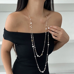 Detail of layered long pearl necklace with golden floral accents on a black dress