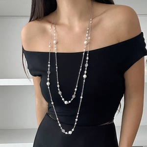 Detail of elegant layered pearl necklace with silver flower hollow beads on a black dress