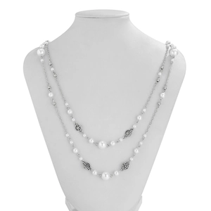 Close-up of double-layered long pearl necklace with silver flower charms on a mannequin