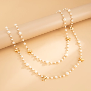 Detail of elegant long pearl necklace with golden butterfly accents on a soft background