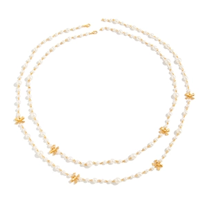Macro detail of white pearl necklace with gold bow accents and lobster clasp