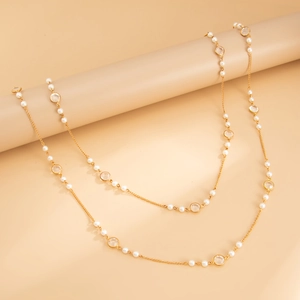 Detailed close-up of long layered necklace with pearls and clear crystal charms