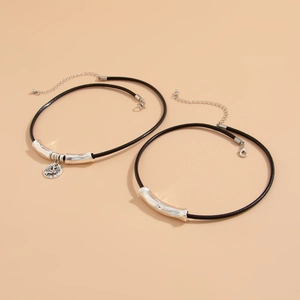 Close-up of layered black leather cords with silver curved tubes and relief pendant