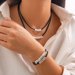 Detail of multi-layer wax cord necklace and bracelet set with silver metal tubes on a model