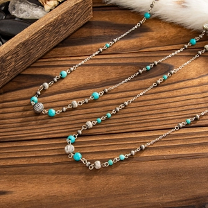 Detail of vintage bohemian silver chain with turquoise beads on textured wood