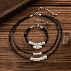 Detail of layered black cord necklace and bracelet set with silver cylindrical pendants