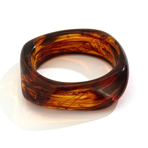 Macro shot of thick tortoiseshell acrylic bangle with translucent amber geometric texture
