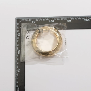 Detail of chunky gold bangle with irregular hammered texture on measuring scale