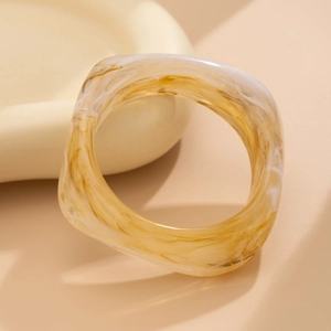 Macro detail of amber and white marble resin bangle with geometric square silhouette