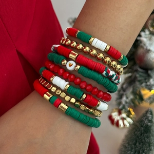 Gros plan de bracelets de Noël superposés avec perles heishi rouges, vertes et blanches