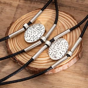 Detail of vintage bolo ties with oval textured metal buckles on a wooden display base