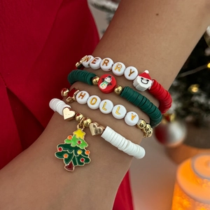Détail de bracelets de Noël empilables avec perles heishi colorées et breloques de fête