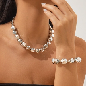Vista de detalle del conjunto de collar y pulsera de perlas plateadas irregulares