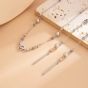 Detail of silver rose pendant and iridescent beads on a vintage multi-layered long necklace