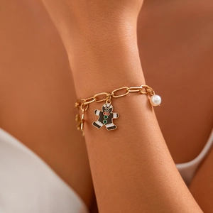 Dettaglio del bracciale festivo dorato con ciondolo a forma di omino di pan di zenzero