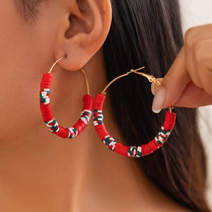 Detail of bohemian red green and white clay bead hoop earrings with gold leverback closure