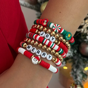 Gros plan de bracelets de Noël en argile colorée avec breloques JOY et MERRY au poignet