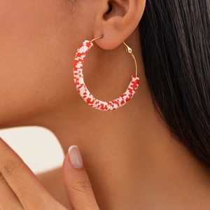 Close-up of bohemian gold hoop earrings with red and white polymer clay heishi beads
