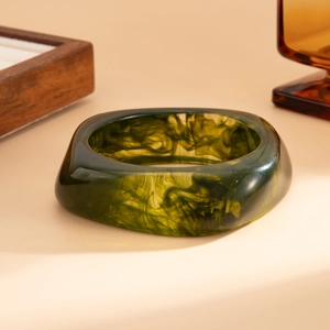 Macro shot of translucent green resin bangle with artistic black ink marble patterns