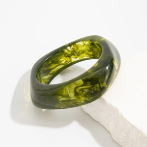 Detailed close-up of translucent dark green acrylic bangle with smoky marble texture