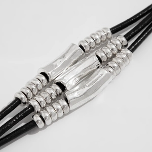 Macro shot of double-layer cord necklace with vintage metal tubes and beads detail