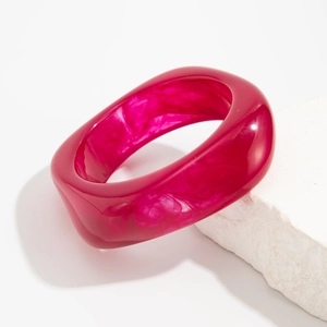 Macro detail of rose red acrylic wide bangle with marble texture on stone display