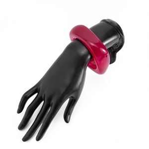 Detail of wide thick acrylic bangle in translucent fuchsia on black hand model