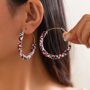 Detailed view of large gold hoop earrings with festive red, white, and green clay beads