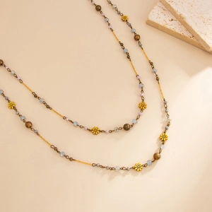 Detail of long pearl beaded necklace with gold flowers and matte lavender beads