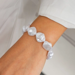 Nahaufnahme eines barocken Perlenarmbands am Handgelenk mit weißer Hemdmanschette
