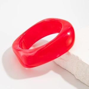Macro detail of a thick translucent red acrylic bangle with irregular geometric design