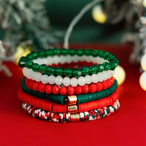 Gros plan d'un ensemble de bracelets de Noël avec perles Heishi rouges, vertes et blanches
