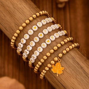 Makroaufnahme des Happy Fall Perlenarmband-Sets mit Goldperlen und Ahornblatt-Anhänger