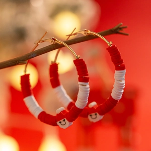 Detail of Christmas hoop earrings with red and white clay beads and Santa Claus charm