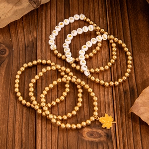 Details von herbstlichen Perlenarmbändern mit Goldperlen und Ahornblatt-Anhänger