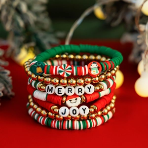 Détail de bracelet de Noël en perles d'argile rouges et vertes avec breloques de fête