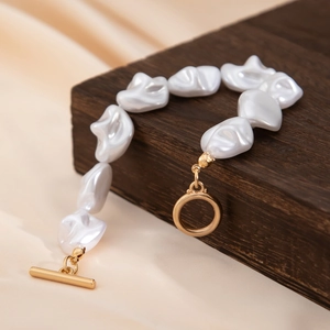 Nahaufnahme des Barockperlenarmbands mit goldener OT-Schließe auf Seidenhintergrund