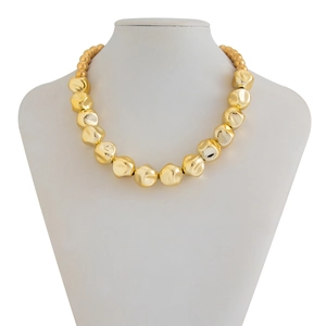 Vista de detalle de un collar dorado con cuentas irregulares sobre un busto de joyas
