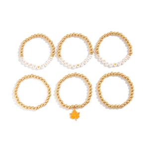 Detailansicht des 6-teiligen goldenen Perlenarmband-Sets mit HAPPY FALL-Schriftzug und Ahornblatt