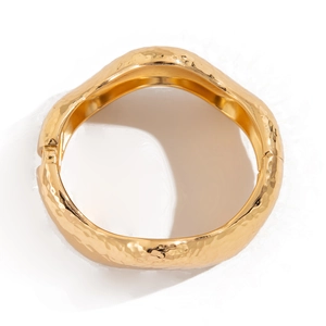 Detail of the golden hammered texture and liquid metal wavy design on the wide cuff bracelet