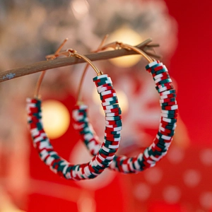 Detailed close-up of Christmas hoop earrings with red, green, and white heishi beads