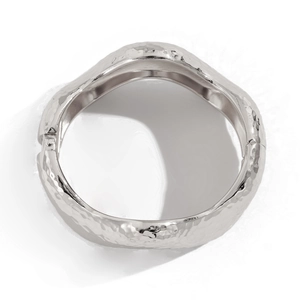 Detail of silver wavy bracelet showing hammered metal texture and side hinge closure