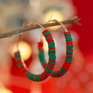 Detailed view of red and green heishi beads on golden festive Christmas hoop earrings