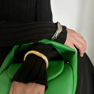 Close-up of irregular wave metal cuff bracelet worn over black knit sleeve styling