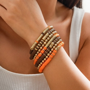 Detail von mehrlagigen Boho-Perlenarmbändern mit orangen Heishi-Perlen und Goldakzenten