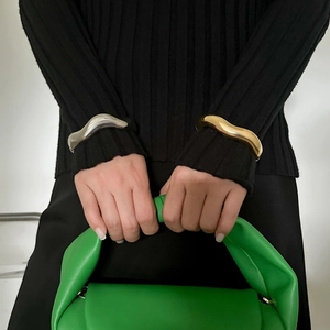 Minimalist wavy metal cuff bracelets in gold and silver finish on a female model
