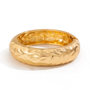 Golden wide cuff bracelet with textured hammered finish and minimalist luxury aesthetic