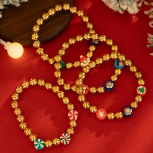 Christmas beaded bracelet set with gold beads, snowman and reindeer charms on red background
