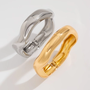 Close-up of wavy gold and silver metal bangles with a polished mirror finish and fluid design